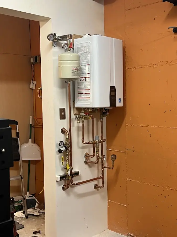 Plumbing technician inspecting water heater connections in Wesley Hills